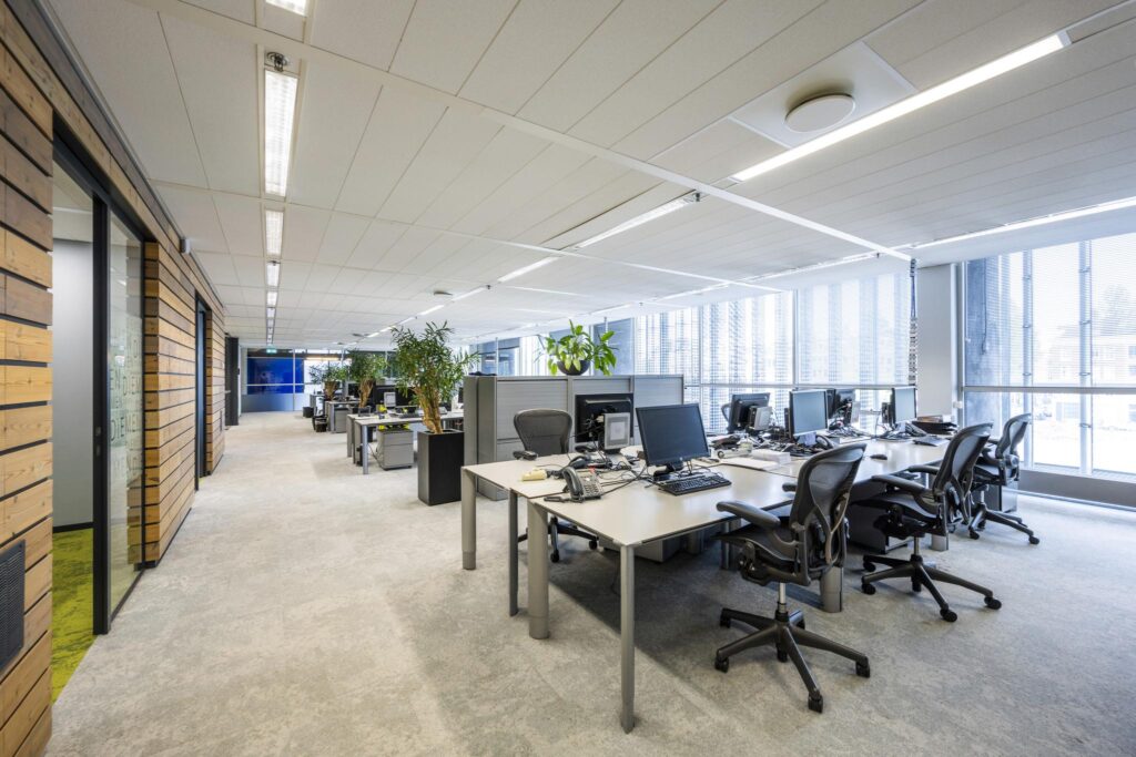 Modern open-plan office interior at Jacob Bontiusplaats with desks, office chairs, and large windows.